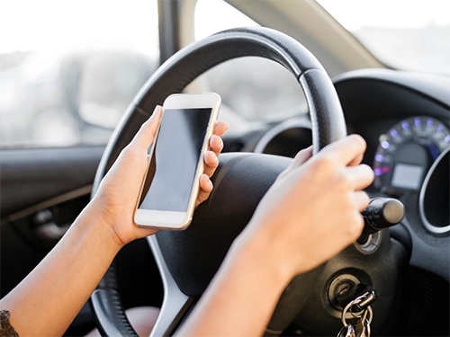 Distracted Driving Attorneys in Carrollton Georgia - Image of a person holding their smartphone while behind the wheel of a car